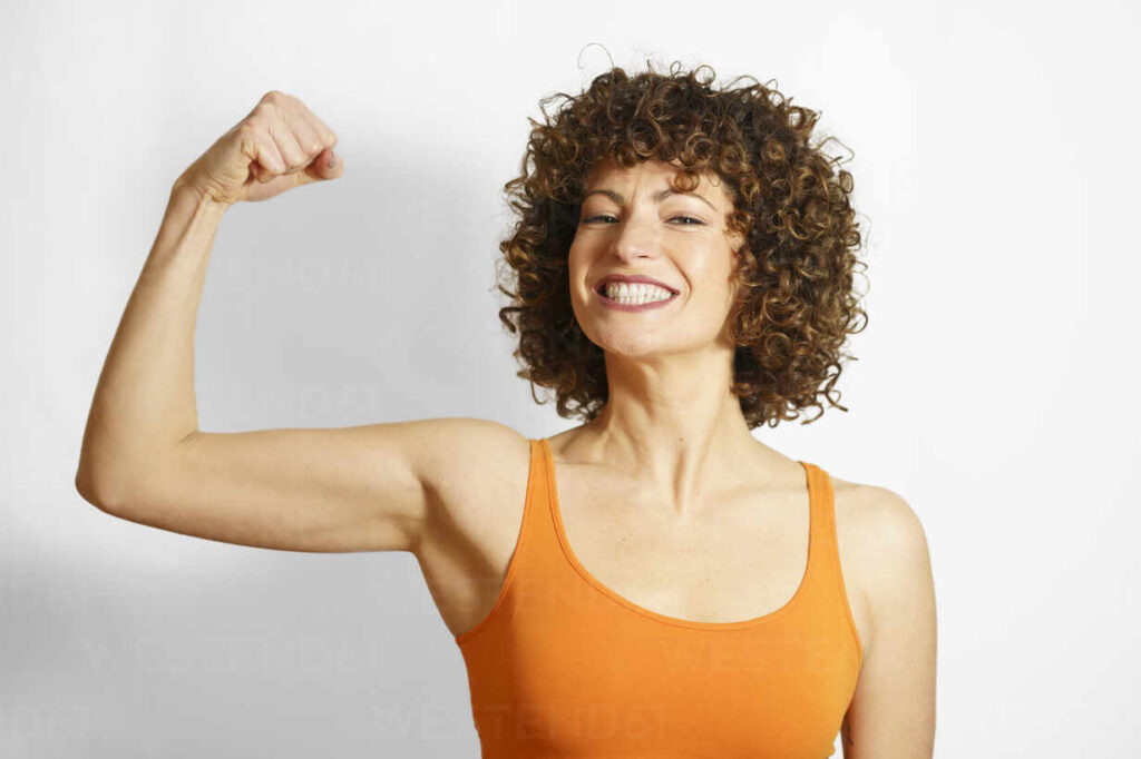 Happy woman flexing muscles against white background